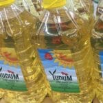 Large yellow plastic bottle of YUDUM Sunflower Oil on a store shelf, bottle label visible.