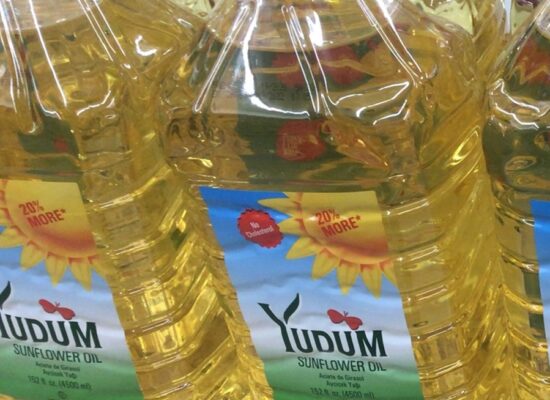 Large yellow plastic bottle of YUDUM Sunflower Oil on a store shelf, bottle label visible.