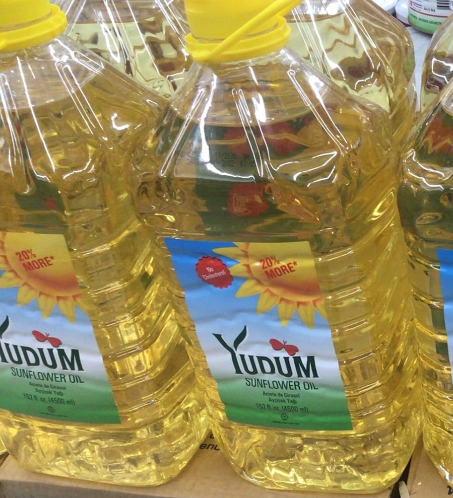 Large yellow plastic bottle of YUDUM Sunflower Oil on a store shelf, bottle label visible.